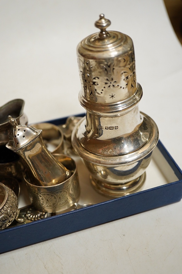 A George V silver sugar caster, Sheffield, 1914, Walker & Hall, together with a four division toast rack, a five peice Edwardian cruet set a/f, a pair of Indian Cutch salts, pair engraved napkin rings, Victorian fiddle,